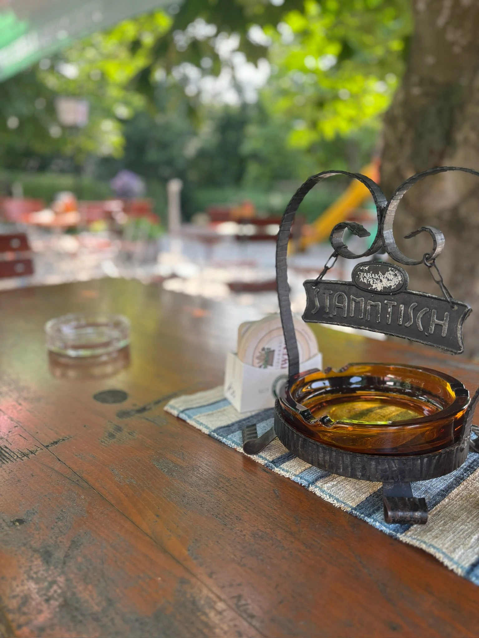 Schmiedeeisernes Stammtisch-Schild auf dem Biergartentisch unter der Kastanie
